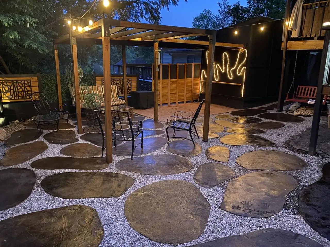 Evening view of finished stained concrete patio discs with pergola and bistro lighting